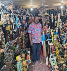 Sculptor auguy in front of his wooden sculptures